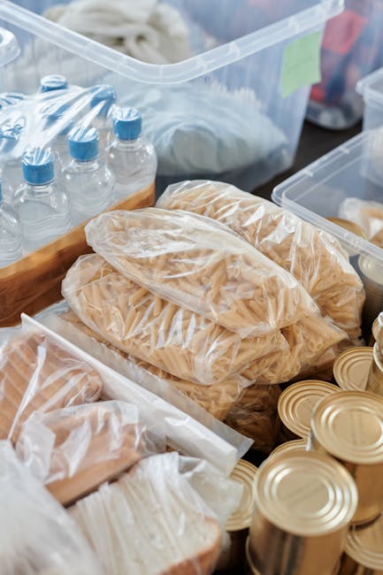 Packed groceries and canned food ready for donation. Includes pasta, water bottles, and bread.